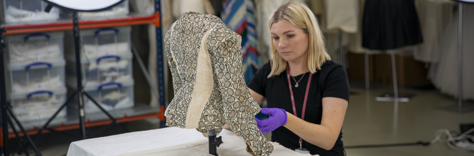 A member of the collections team inspects a historic jacket