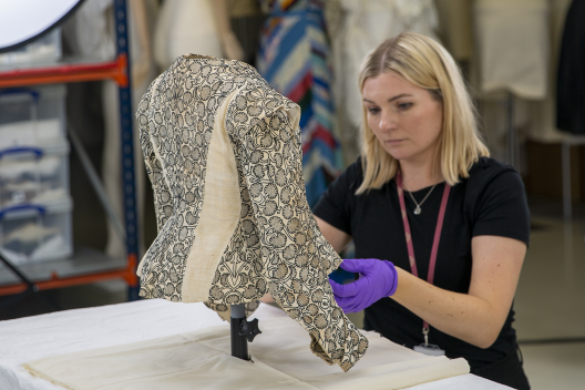 A member of the collections team inspects a historic jacket