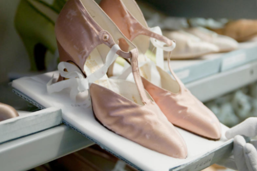 A pair of soft pink shoes are shown in storage in the Fashion Collection Archive 